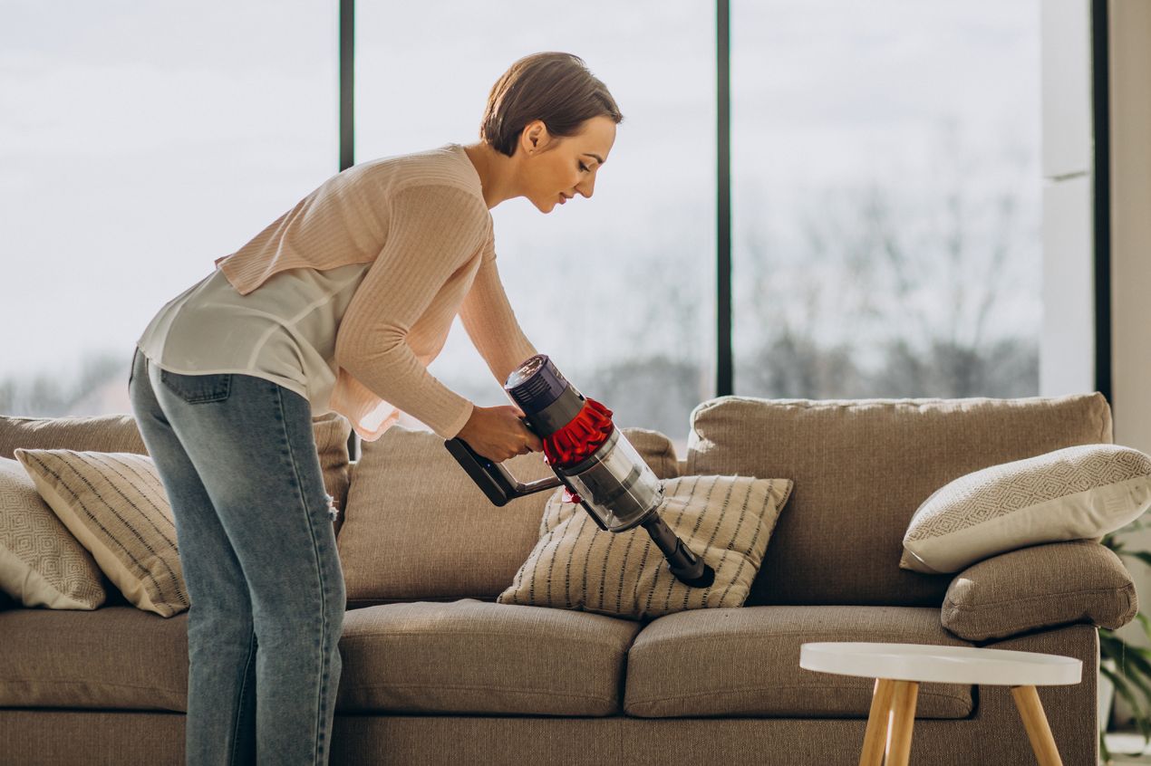 young-woman-with-rechargeable-vacuum-cleaner-cleaning-home